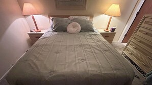 A neatly made bed with a quilted cover, two bedside lamps, and a wooden nightstand. - Charming 2-bedroom condo in serene Lake Suzy with WiFi, AC (Lake Suzy)