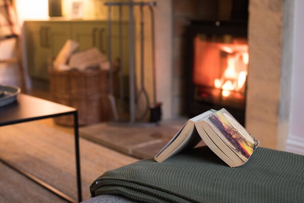 A cozy room with a fireplace, a table, and a green knitted blanket.