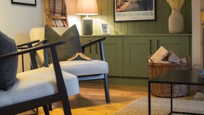 A living room with a sofa, armchairs, a lamp, a framed picture, a wicker basket, and a table. - Stunning property in the beautiful market town of Stow-on-the-Wold - Devon House Cottage (Stow-on-the-Wold)