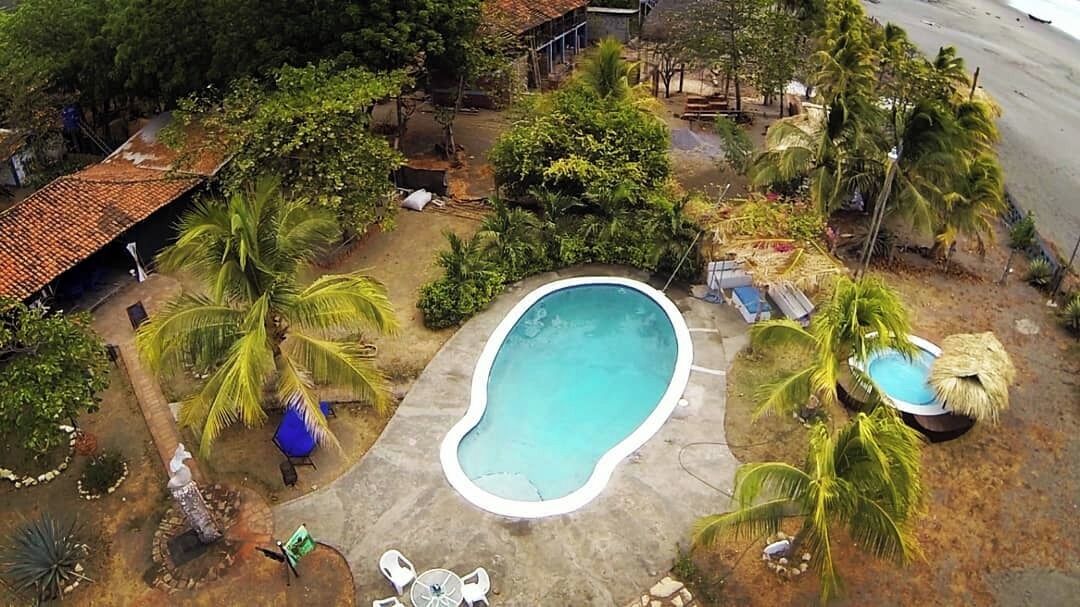 Vista aérea de una propiedad residencial con piscina, palmeras y un pequeño jardín.