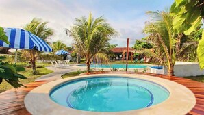 A pool area with a hot tub, palm trees, and lounge chairs. - Somar Surf lodge (León)