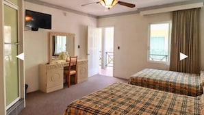 A hotel room with two beds, a desk with a chair, a television, and a large window with curtains. - Hotel Real Santa Rosa (Morelia)
