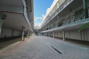 Un pasillo peatonal cubierto con una escalera central, que conecta varios niveles de un edificio.