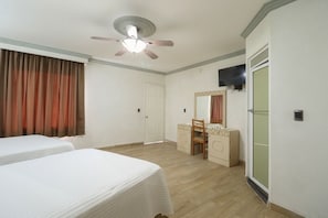 A hotel room with two beds, a ceiling fan, a mirror, a vanity, and a sliding door. - Hotel Real Santa Rosa (Morelia)