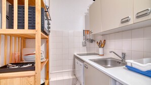 A compact kitchen with white cabinets, a dishwasher, and a sink. - Le Cocon des 3 Domaines - Appt pour 4 (Ax-les-Thermes)
