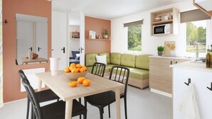 Una cocina moderna con comedor, un sofá verde y una mesa con naranjas.