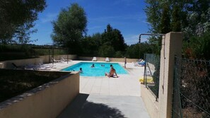 Ein Swimmingpool mit Liegestühlen und einem umzäunten Bereich.