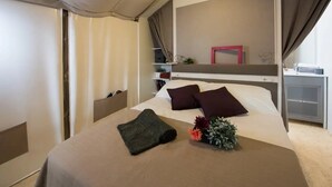 A hotel room with a bed, a bedside table, a nightstand, a dresser, a mirror, and a window with curtains. - ZEcamping 4 étoiles pataugeoire club enfant jacuzzi locatif clim 20m2 (Alghero)