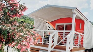 Un bâtiment rouge et blanc doté d’un porche abrité et d’un escalier en bois menant à un toboggan.