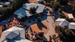 Eine Luftaufnahme eines Resorts mit mehreren Gebäuden, Sitzbereichen im Freien und Sonnenschirmen.
