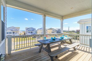 A wooden deck with a picnic table and chairs, overlooking a row of houses. - Sun Realty gorgeous Kitty Hawk home with elevator, just steps from the beach (Kitty Hawk)