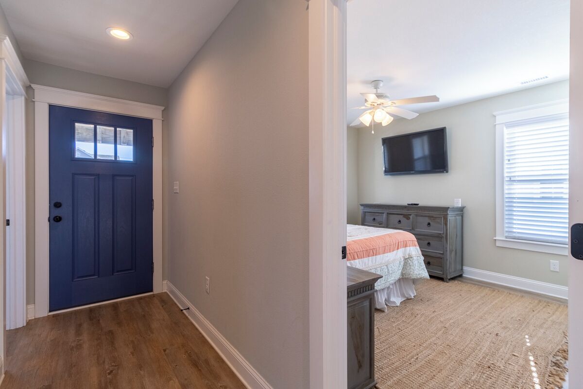 A bedroom with a bed, dresser, and a ceiling fan.