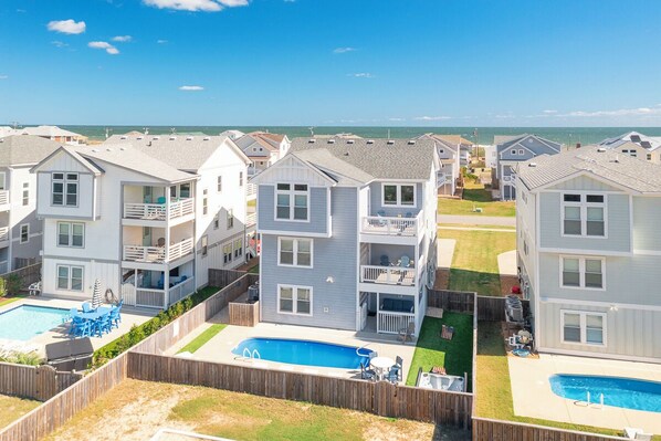 A residential complex with multiple two-story buildings, each featuring balconies and a swimming pool. - Sun Realty gorgeous Kitty Hawk home with elevator, just steps from the beach (Kitty Hawk)