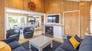 A spacious living area with a fireplace, leather sofas, and a television. - Sun Realty warm Duck NC vacation rental, just a short walk to the beach (Duck)