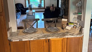 A kitchen with wooden cabinets, a marble countertop, and a stone wall.