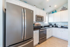 Una cocina moderna con electrodomésticos de acero inoxidable, armarios blancos y piso de madera.