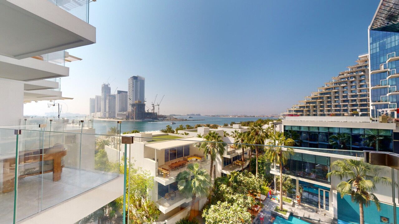Un hotel moderno con piscina en la azotea, barandillas de vidrio y vistas al horizonte urbano y al agua.
