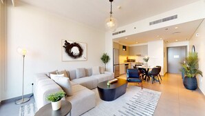 Una sala moderna con un sofá seccional, una mesa de centro y un comedor con sillas.