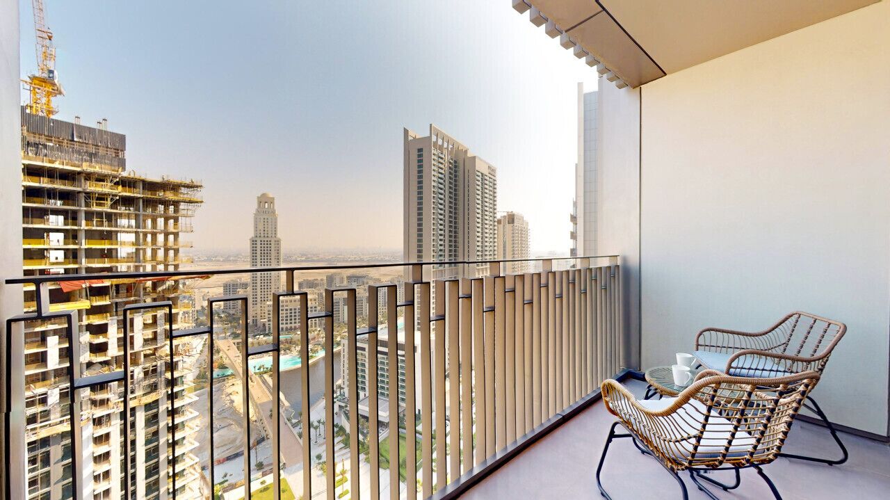 Un balcon offrant une vue sur le paysage urbain, avec notamment des immeubles de grande hauteur et des chantiers de construction.