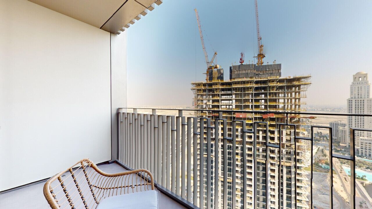 Un balcón con vista a una obra en construcción y un rascacielos al fondo.