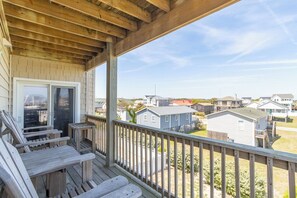A wooden deck with outdoor seating, a covered area, and a view of neighboring houses.