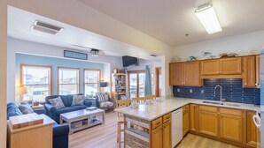 Une cuisine moderne avec des meubles en bois, un îlot central et un coin repas comprenant un canapé et une table basse.