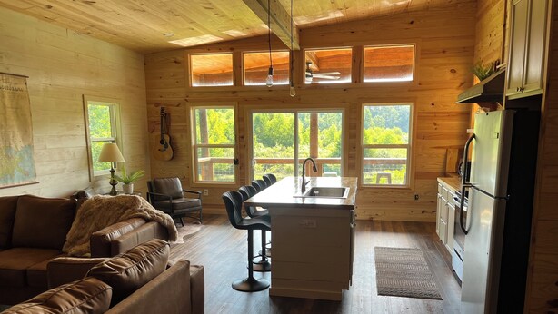 Un intérieur de chalet chaleureux, avec un revêtement en bois, un coin repas et une cuisine.