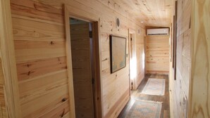 Un couloir intérieur aux murs en bois, avec une porte, un tableau encadré et un tapis à motifs.