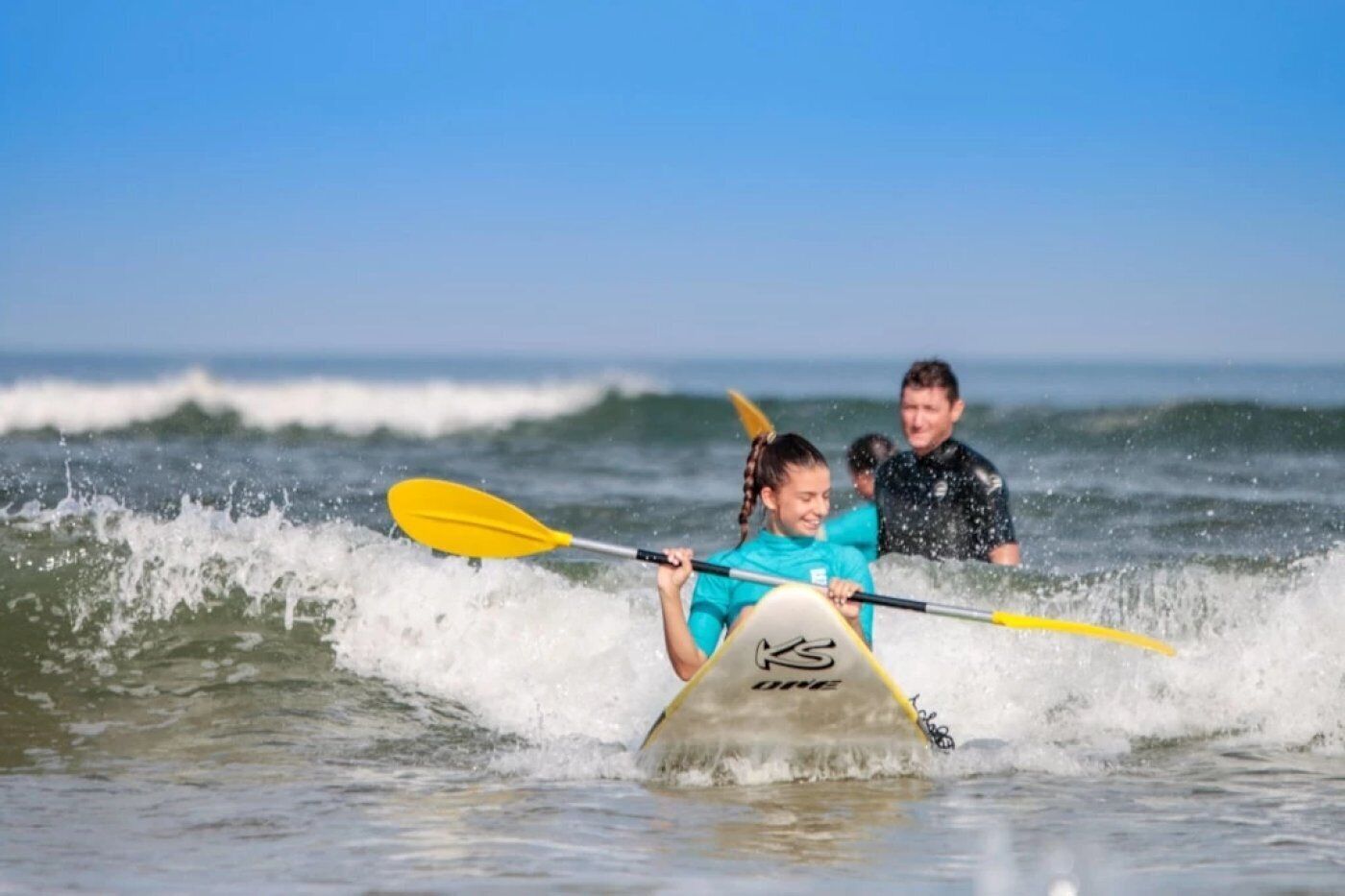 A person kayaking with a paddle and a surfboard.
