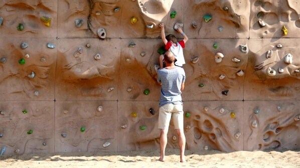 A person climbing a large rock climbing wall with various holds.