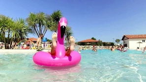 A pool area with clear water, palm trees, and people swimming. - ZEcamping 4 étoiles parc aquatique 1km plage club enfant locatif clim (Mimizan)