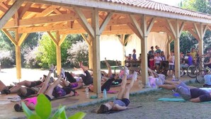 Ett takförsett utomhusområde där människor ligger på mattor, troligen för en grupptränings- eller yogapass.