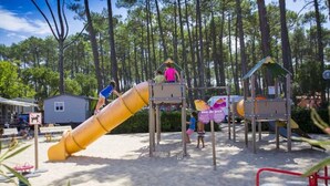 A playground with a yellow slide, climbing structures, and a small shelter. - ZEcamping 4 étoiles 500m plage espace aquatique locatif 28m2 (Seignosse)