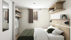 A modern bedroom with a bed, built-in shelving, a mirror, and a window with curtains. - ZEcamping 4 étoiles piscine couverte toboggans locatif 28m2 4 pers (Névez)