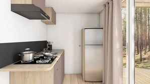 A compact kitchen with a stove, pots, and a refrigerator. - ZEcamping 4 étoiles piscine couverte toboggans locatif 28m2 4 pers (Névez)