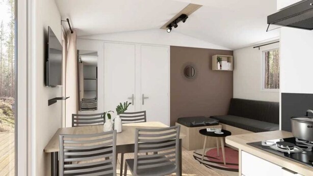 A modern kitchen with a dining area, a built-in oven, and a seating area with a sofa and a small table. - ZEcamping 4 étoiles piscine couverte toboggans locatif 28m2 4 pers (Névez)