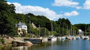 A marina with boats docked, surrounded by lush greenery and houses. - ZEcamping 4* piscine couverte toboggans locatif 28m2 6 pers (Névez)