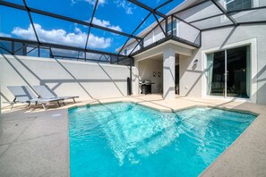 Ein Schwimmbad mit Liegestühlen, einer überdachten Terrasse und Blick auf den Himmel.