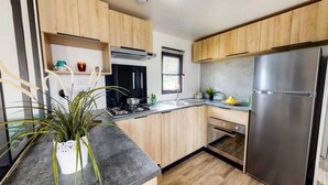 Una cocina moderna con armarios de madera, un refrigerador de acero inoxidable y un horno empotrado.