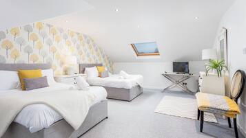A modern bedroom with two beds, a desk, and a chair.