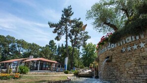 A stone wall with a waterfall and a building with a red roof.