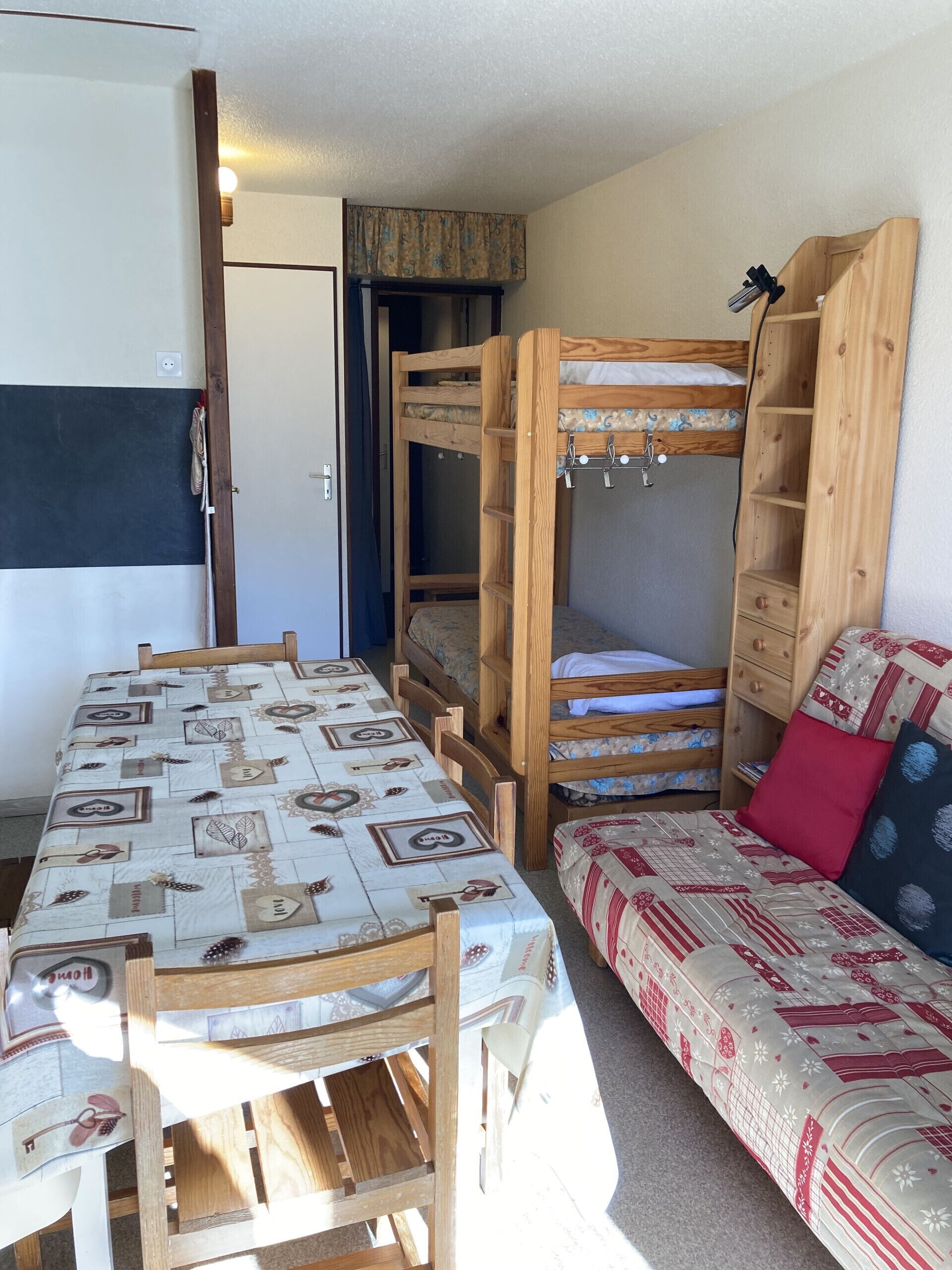 Ein Zimmer mit Etagenbett, einer Schlafcouch, einem Tisch und einer Tischdecke mit Muster.