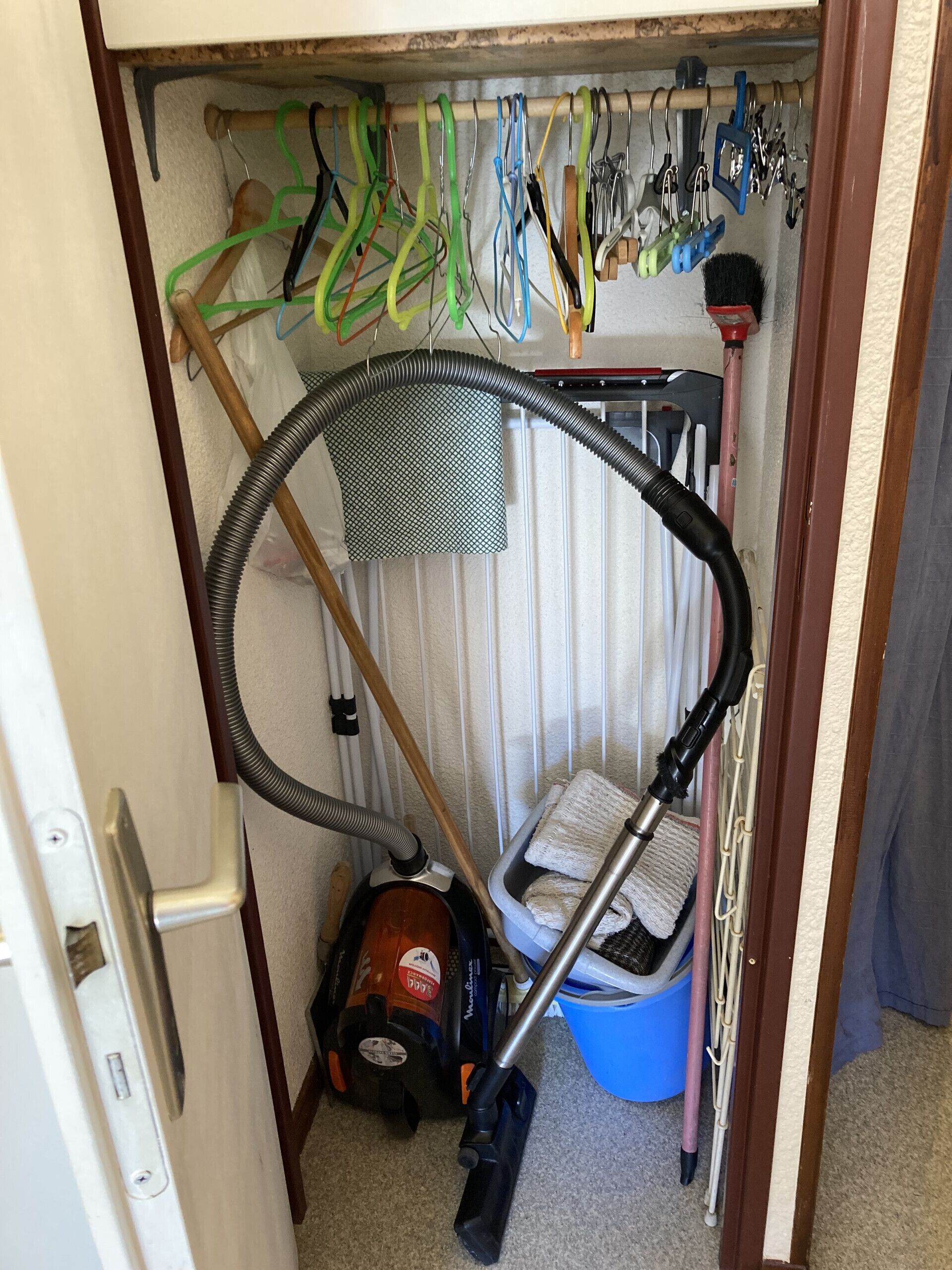 A storage area with a vacuum cleaner, a mop, and cleaning supplies.