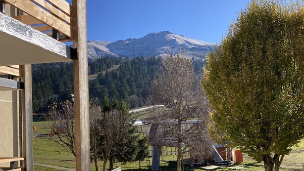 Un ponte in legno con vista su una montagna e un albero sullo sfondo.