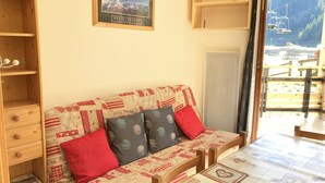 Una stanza accogliente con un divano in legno, un piccolo mobiletto e un quadro incorniciato appeso al muro.