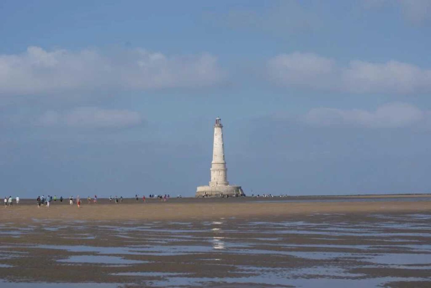 A lighthouse on a sandy beach with a clear sky.