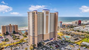 Ein hoch aufragendes Hotel mit mehreren Etagen, einem Parkplatz und Blick auf Strand und Meer.