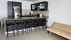 Una cocina moderna con una isla central, taburetes de bar y un sofá.