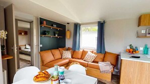 A compact living space with a sofa, a dining table, and a kitchenette. - ZEcamping 4* animé parc aquatique animaux acceptés locatif clim 36m2 (Lège-Cap-Ferret)