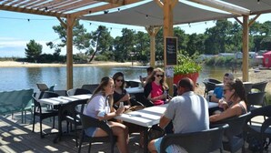 An outdoor patio with tables and chairs, overlooking a body of water.
